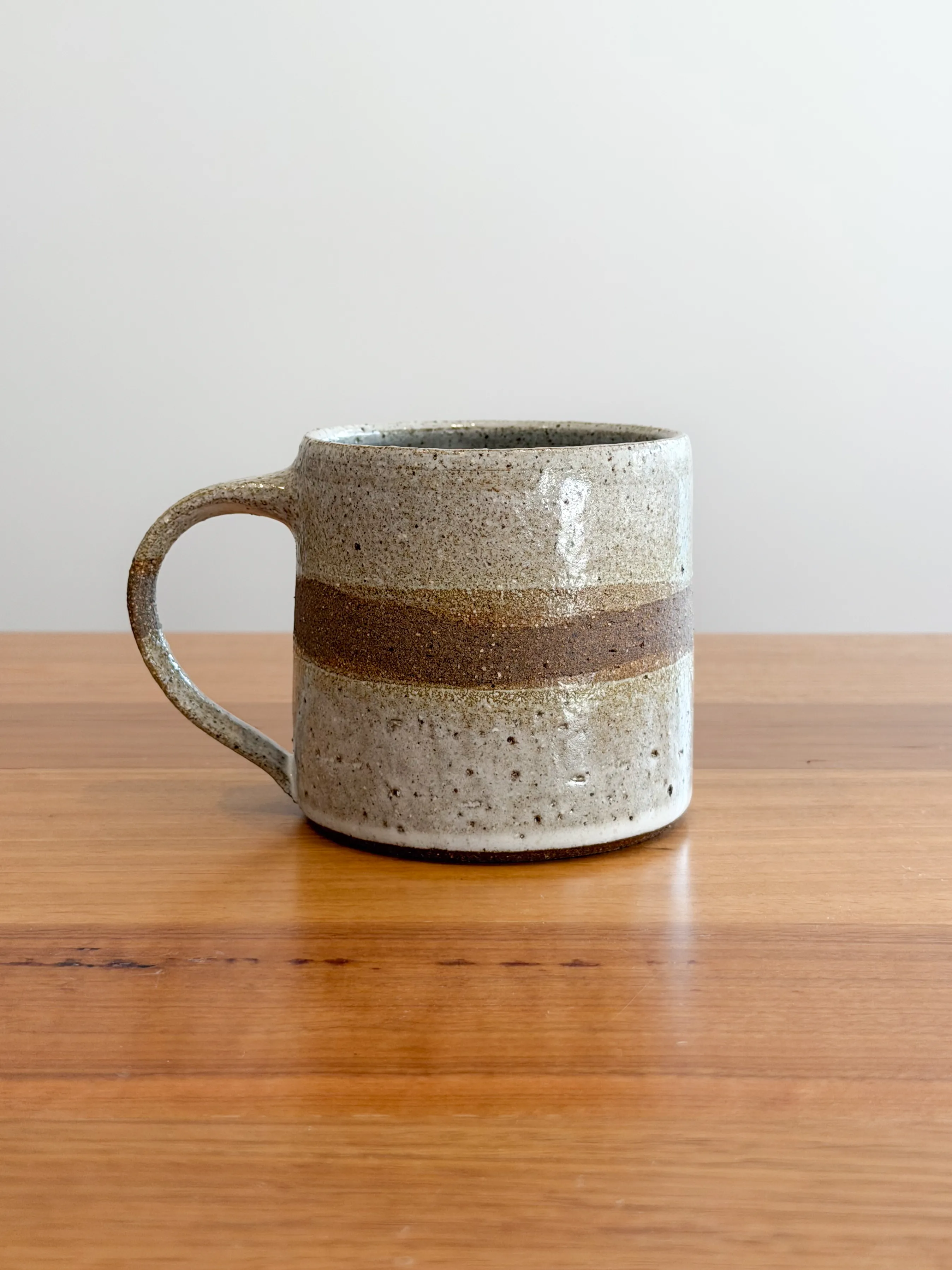 Stoneware mug with white glaze and a band of exposed dark clay