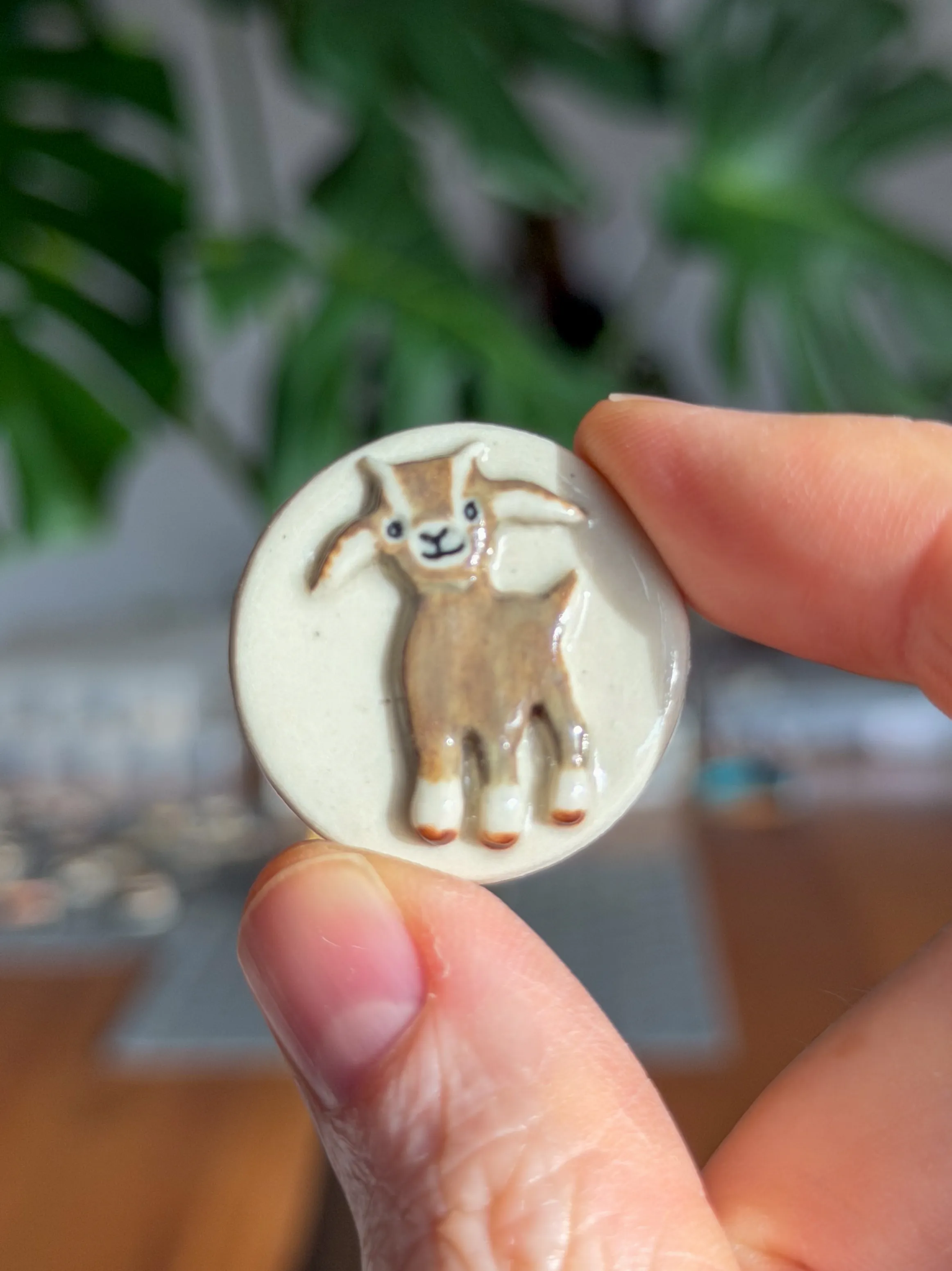 Hand-sculpted ceramic brooch of a brown-and-white goat