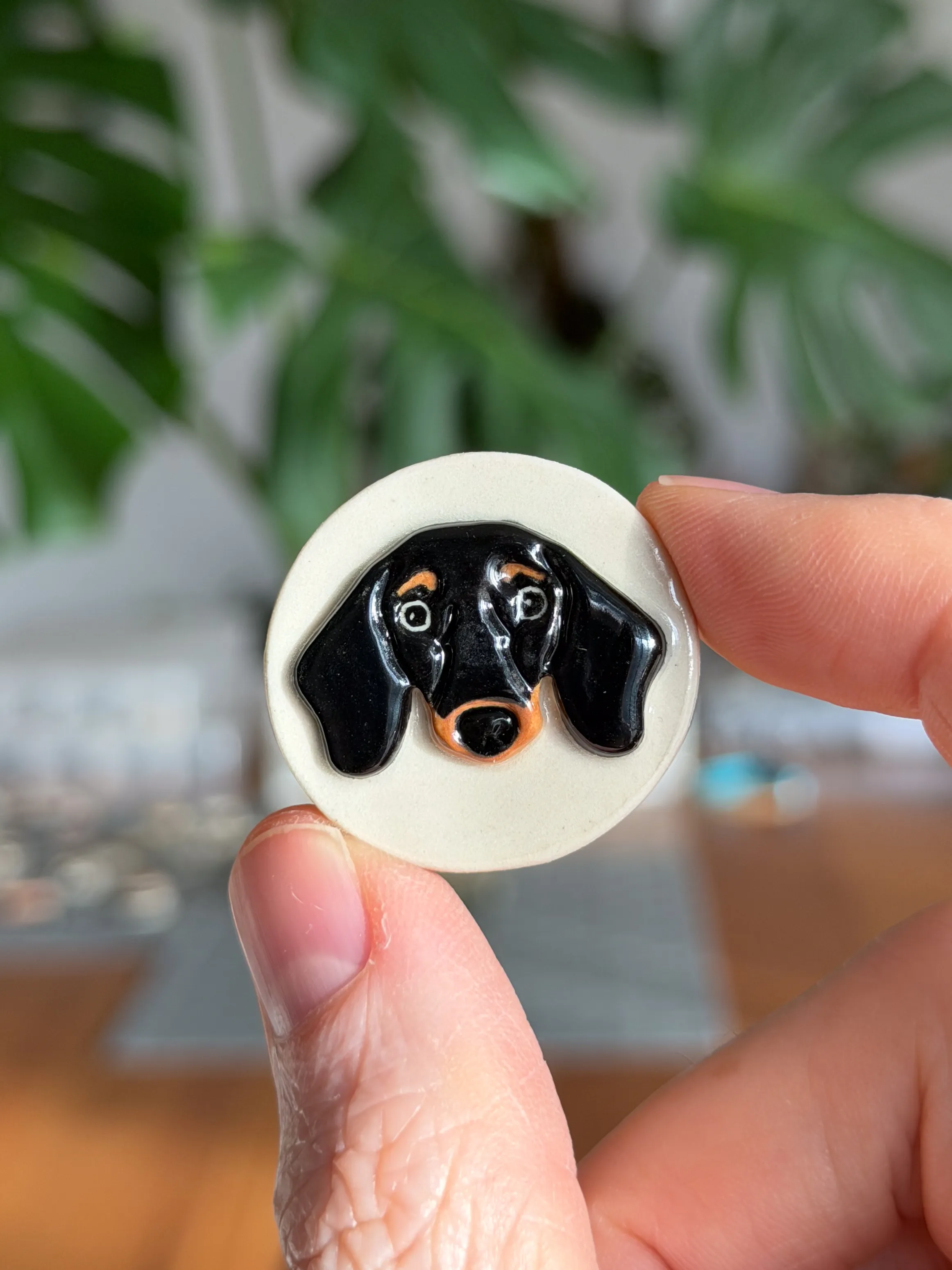 Hand-sculpted ceramic brooch of a black dachshund face