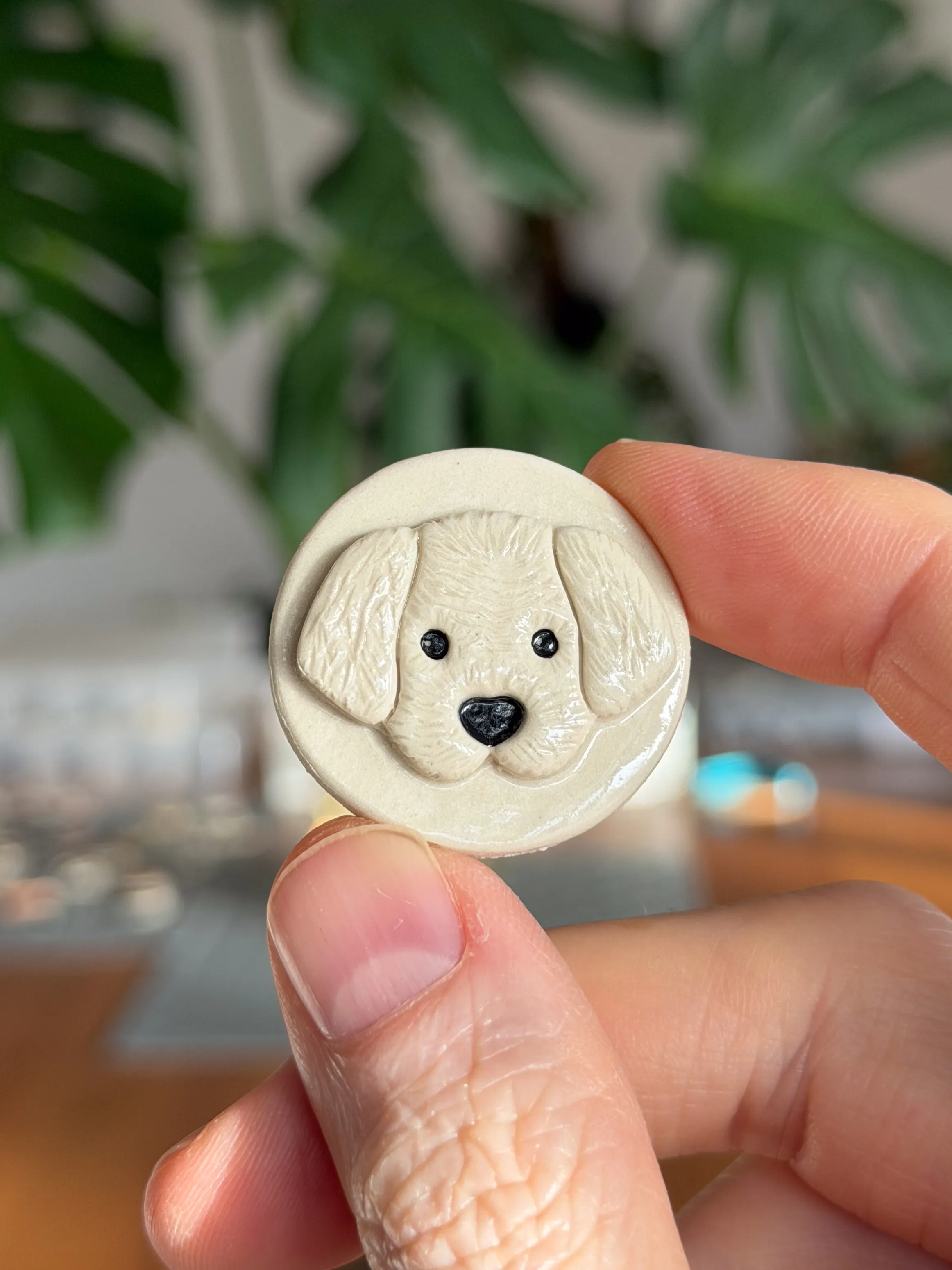 Hand-sculpted ceramic brooch of a cream puppy face