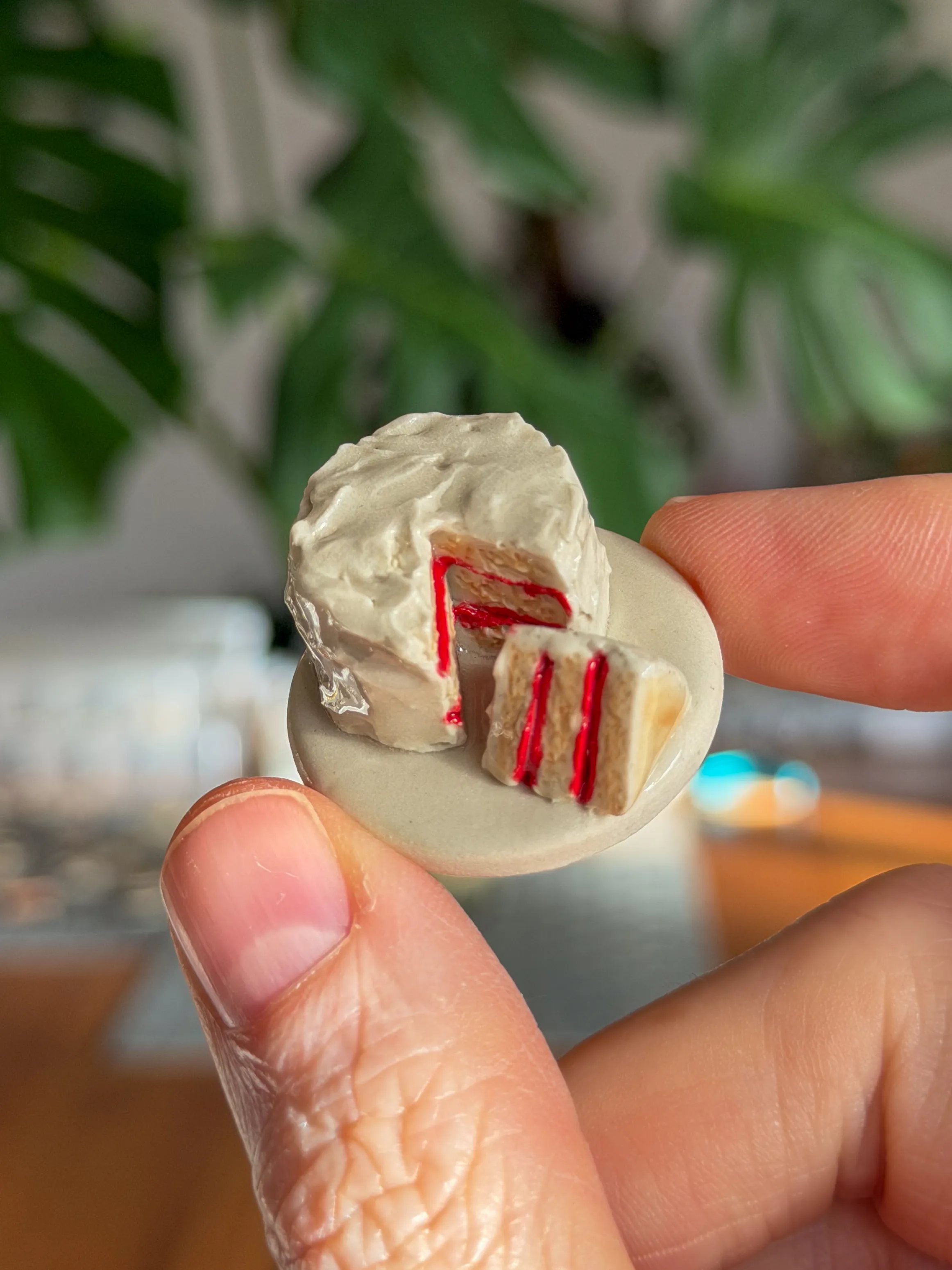 Hand-sculpted ceramic brooch of a frosted layer cake with red filling
