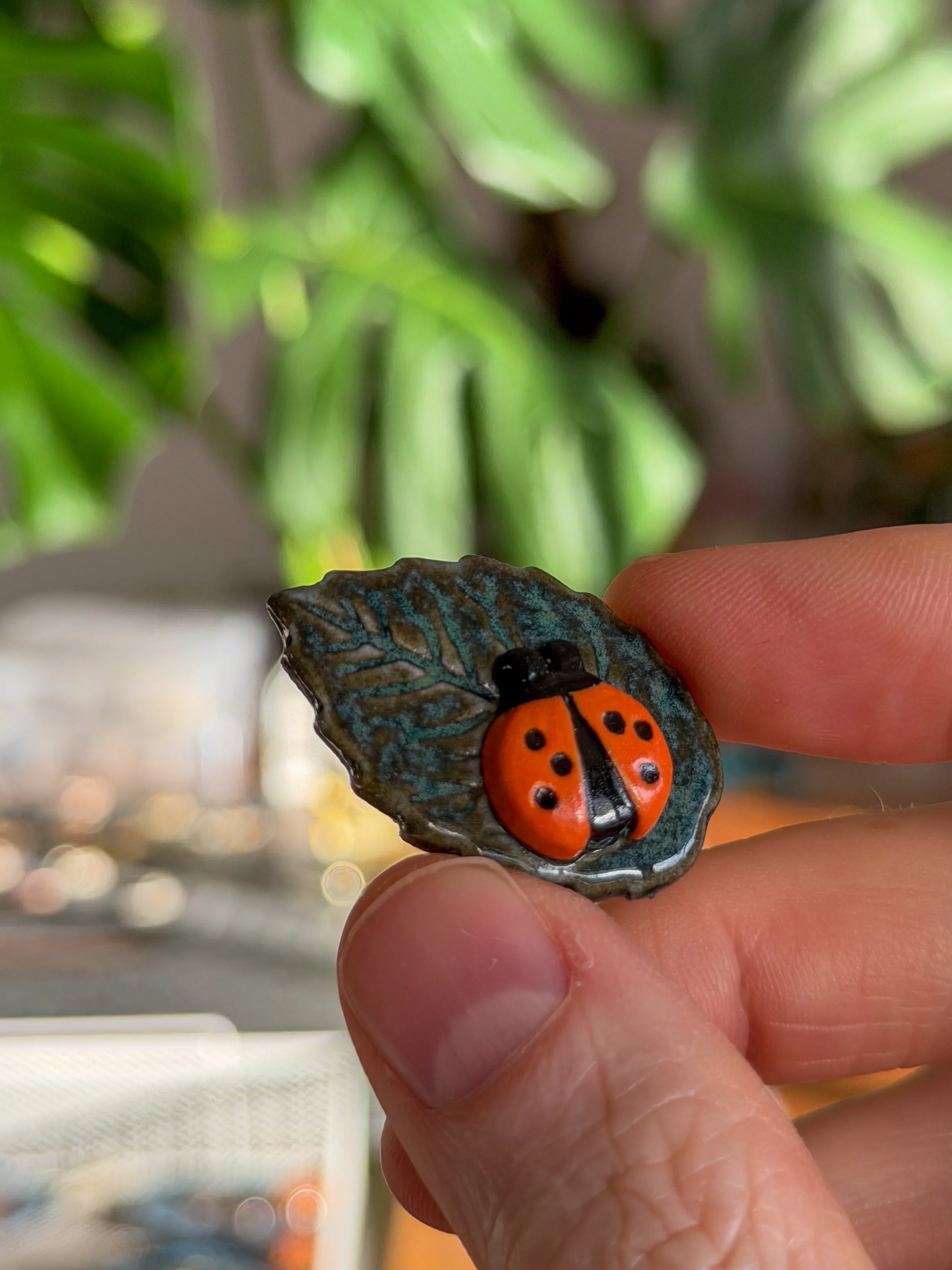 Leaf-shaped ceramic brooch with a sculpted red ladybug