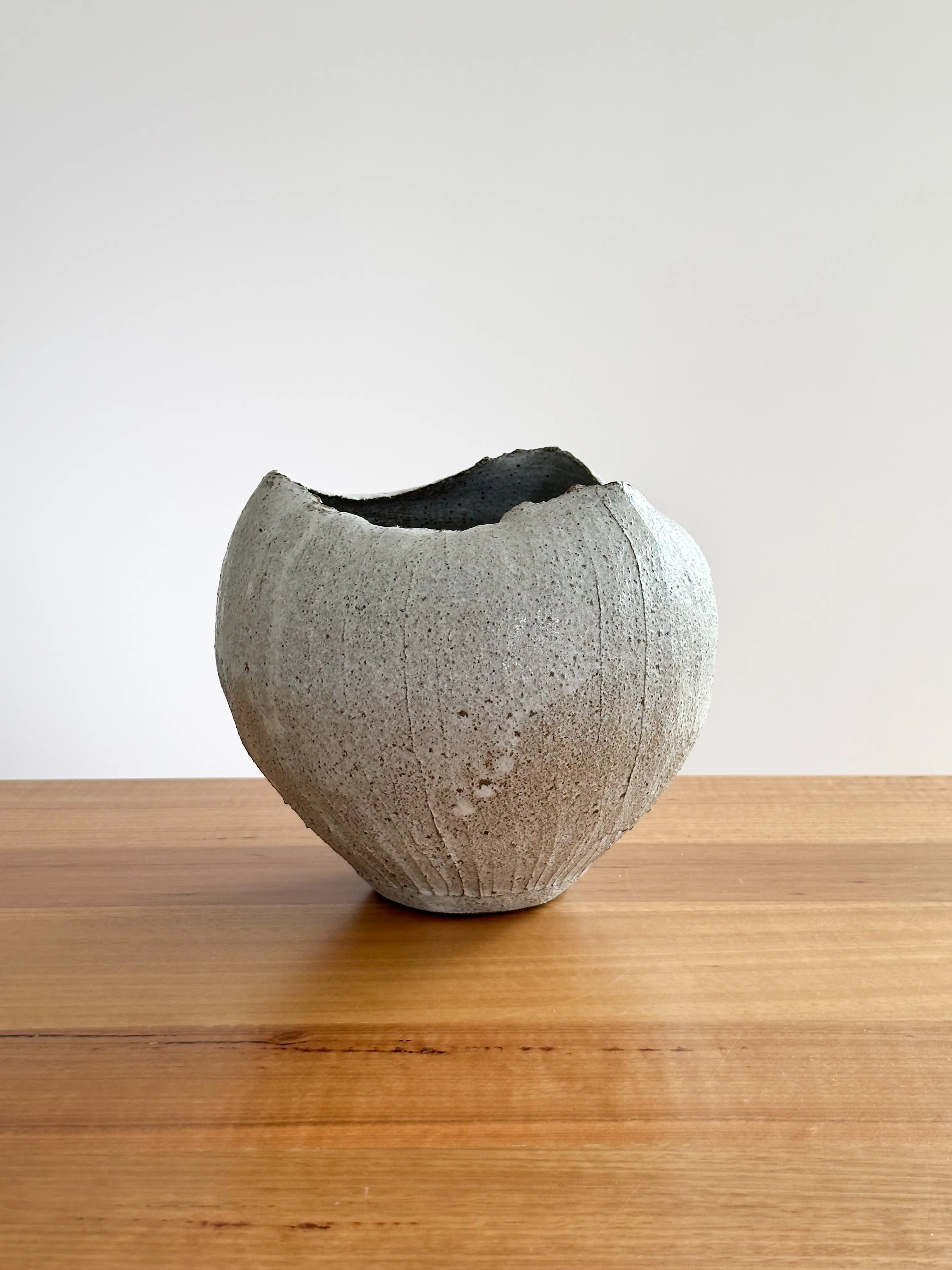 Rounded stoneware vessel with rough grey glaze and natural rim
