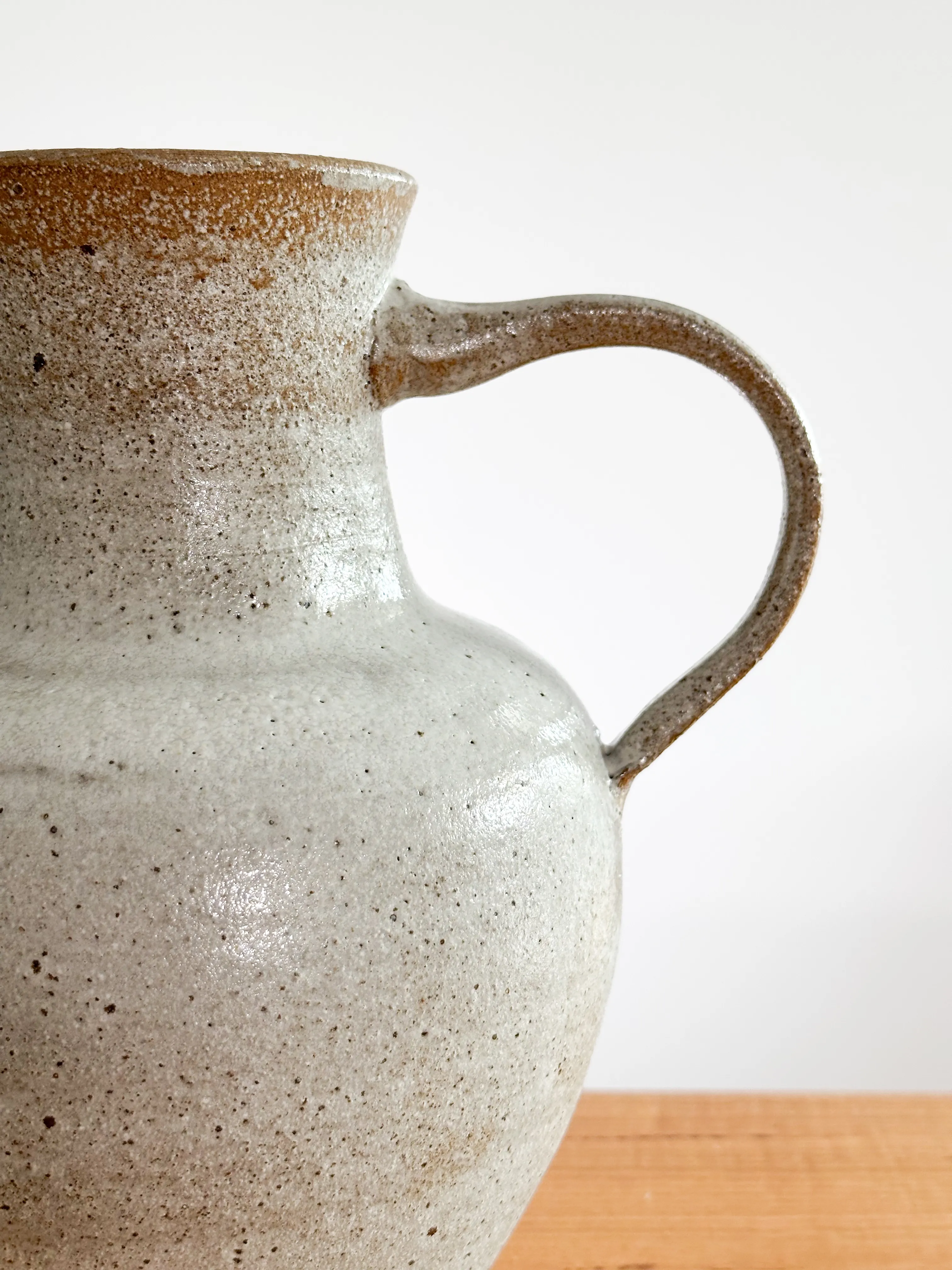 Close-up of a stoneware jug handle and shoulder with speckled white glaze