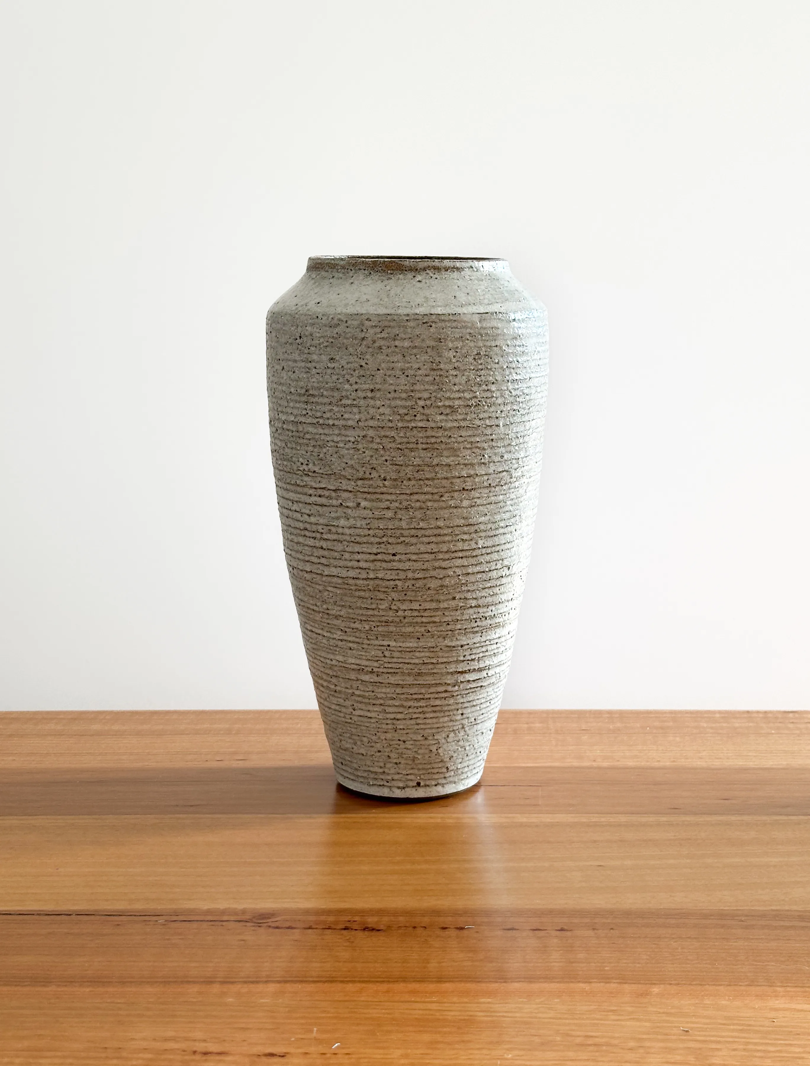 Tall stoneware vase with horizontal wheel ribs and dark clay showing through speckled glaze